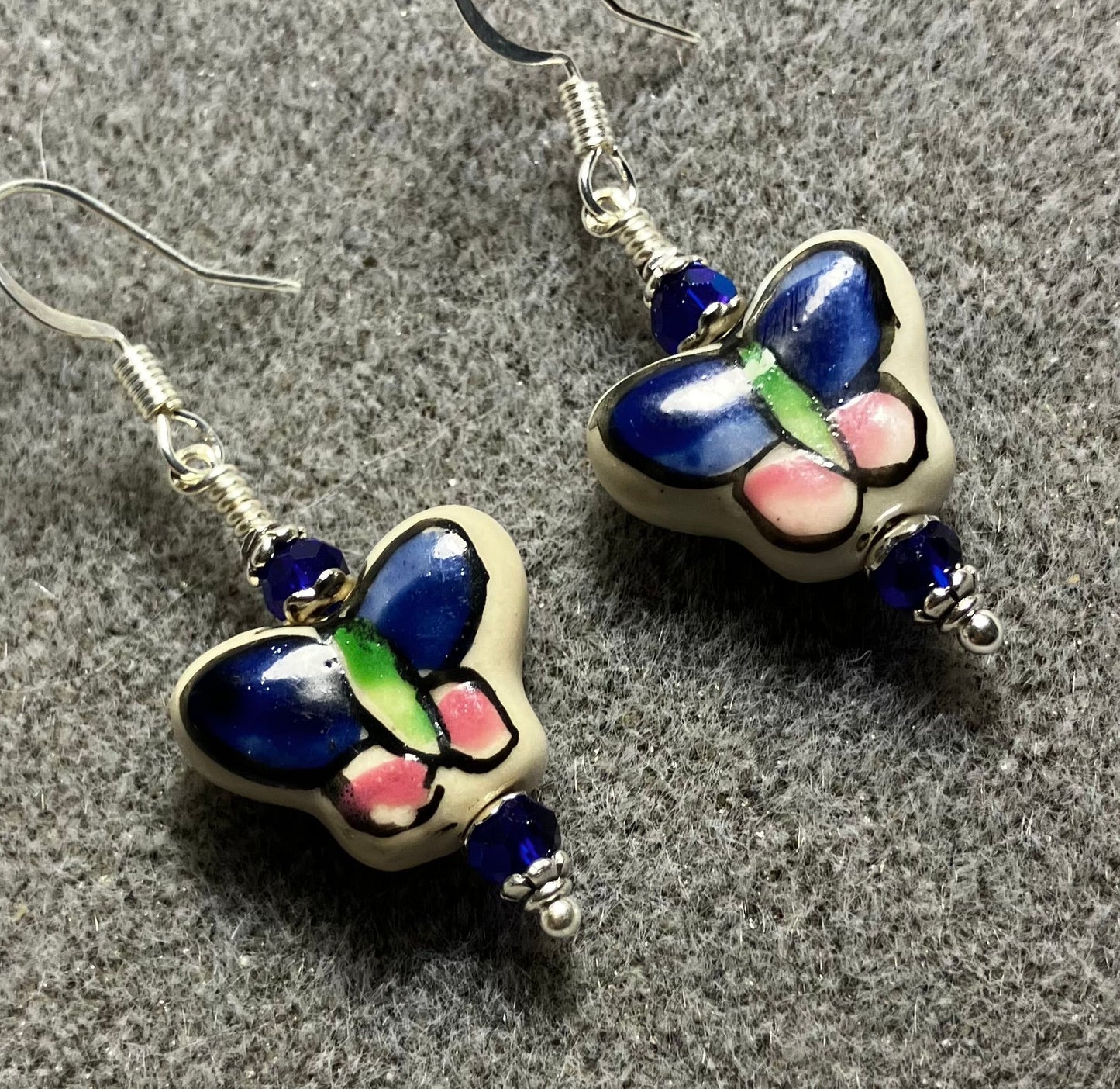 Dark blue, pink, and green ceramic butterfly bead earrings adorned with dark blue Chinese crystal beads.