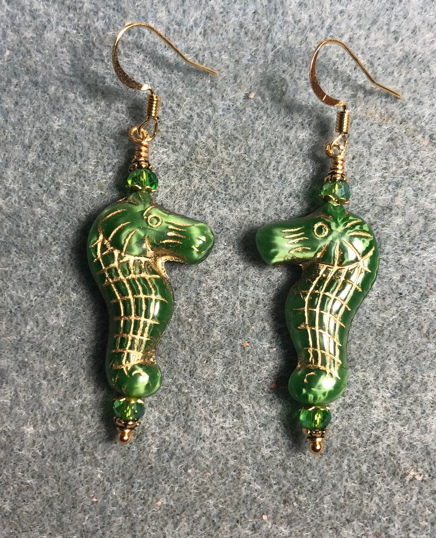 Green (with gold inlay) Czech glass seahorse bead earrings adorned with green Chinese crystal beads.