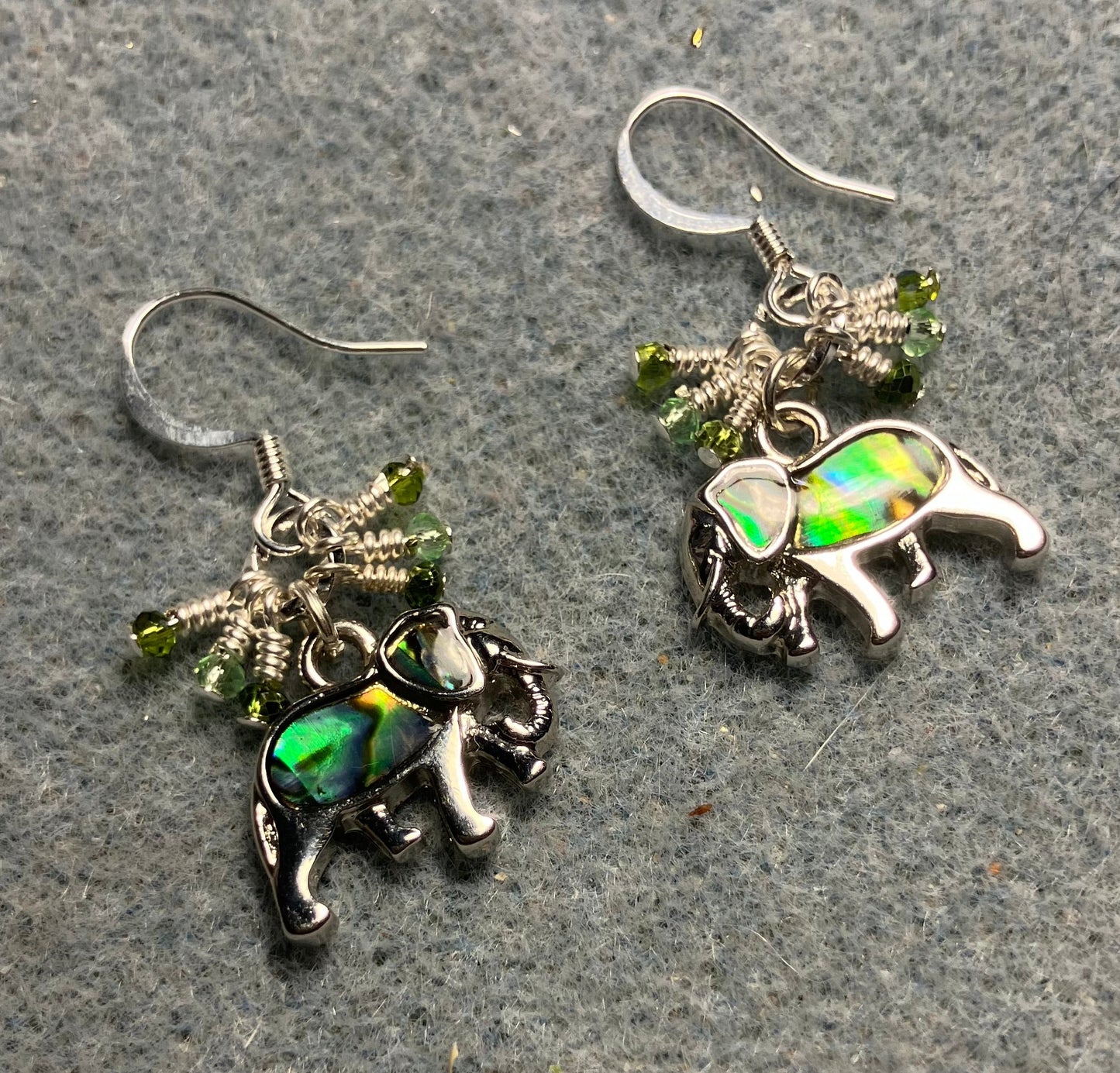 Small silver and abalone elephant charm earrings adorned with tiny dangling green Chinese crystal beads.