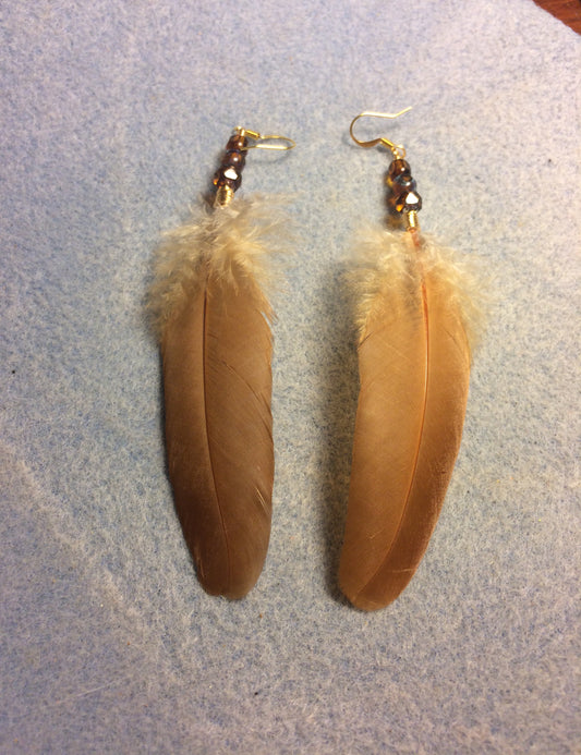 Orange chicken feather earrings adorned with amber Czech glass beads.