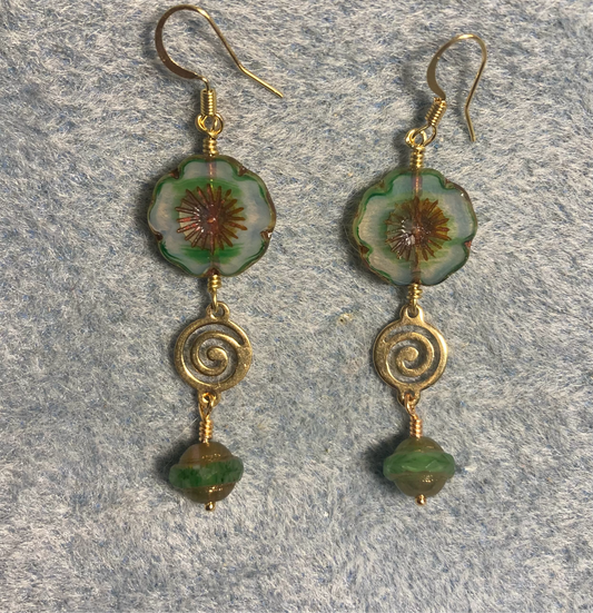 Emerald green Czech glass pansy bead earrings adorned with gold swirly connectors and emerald green Czech glass Saturn beads.