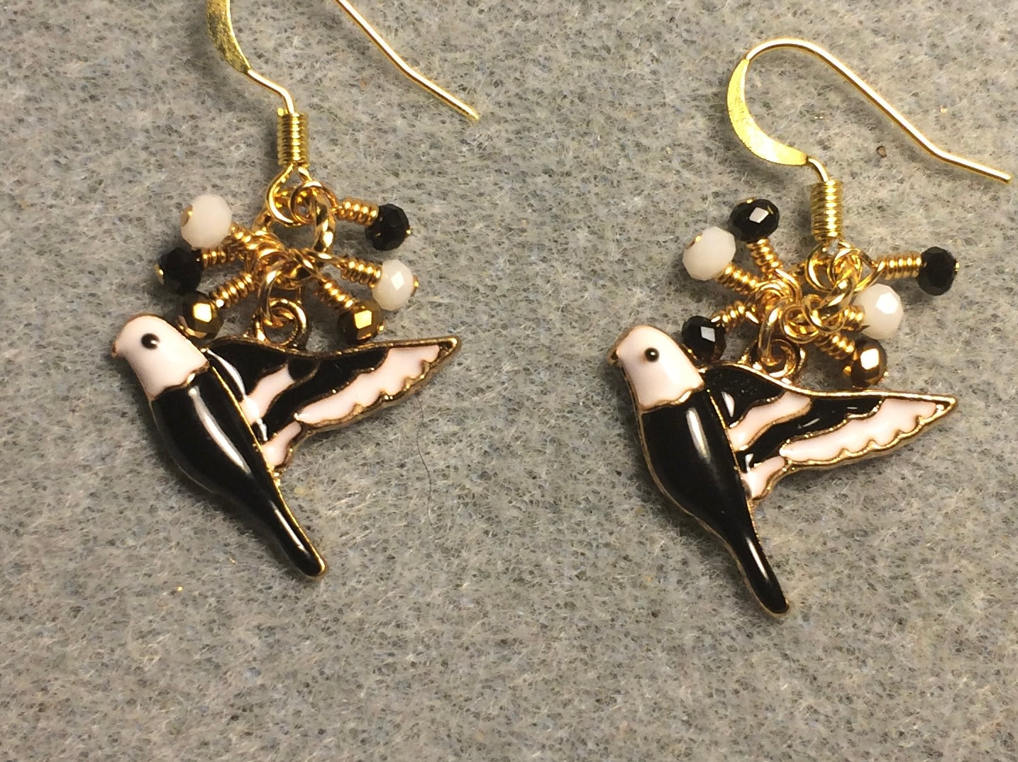 Black, white, and gold enamel parakeet charm earrings adorned with tiny dangling black, white, and gold Chinese crystal beads.