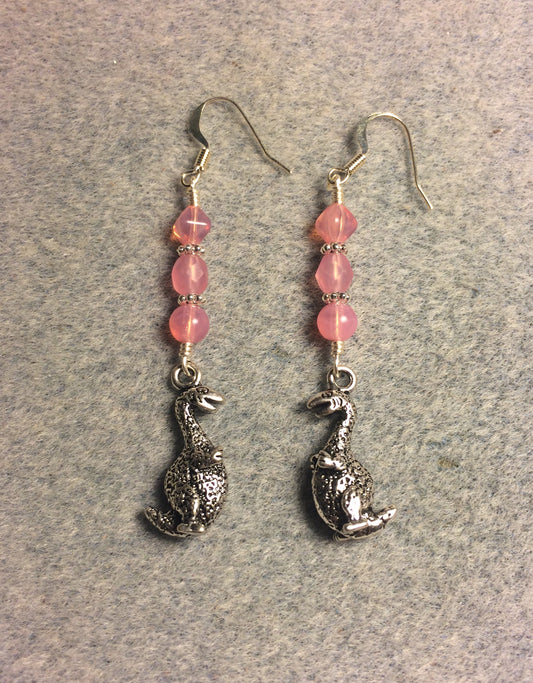 Silver dinosaur charm earrings adorned with milky pink Czech glass beads.