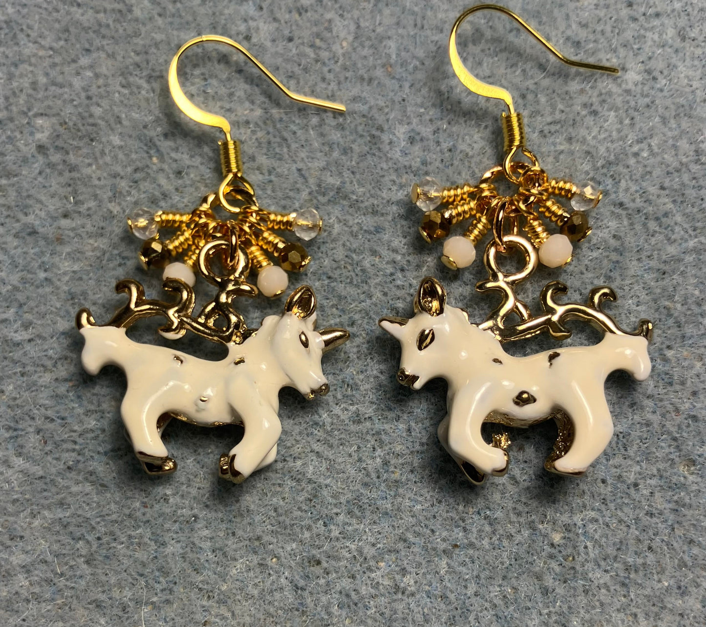 White and gold enamel unicorn charm earrings adorned with tiny dangling white, gold, and clear Chinese crystal beads.