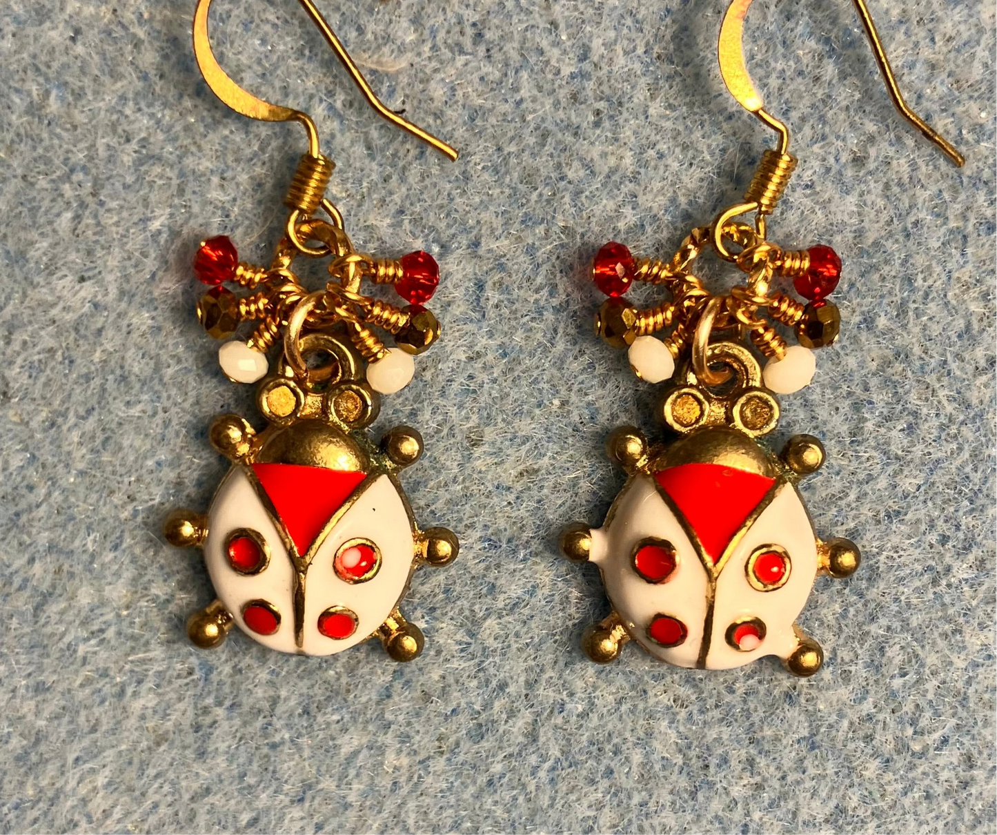 Red, white, and gold enamel ladybug charm earrings adorned with tiny dangling red, white, and gold Chinese crystal beads.