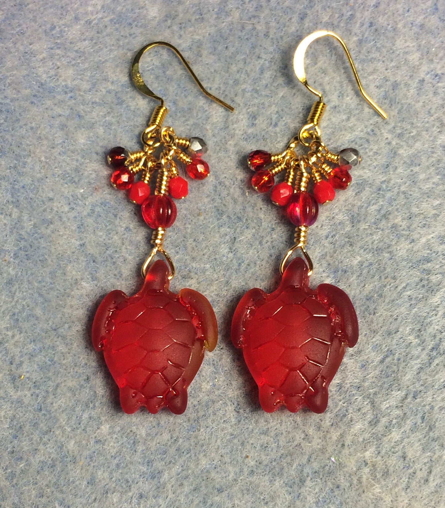 Translucent red sea glass sea turtle bead earrings adorned with red Czech glass beads and small dangling red Czech glass beads.