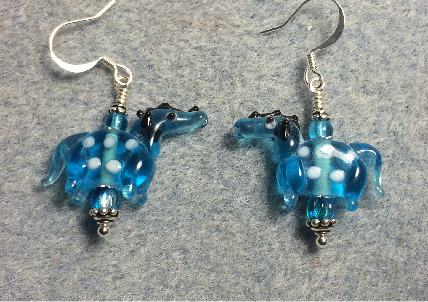 Translucent turquoise lamp work spotted horse bead earrings adorned with turquoise Czech glass beads.