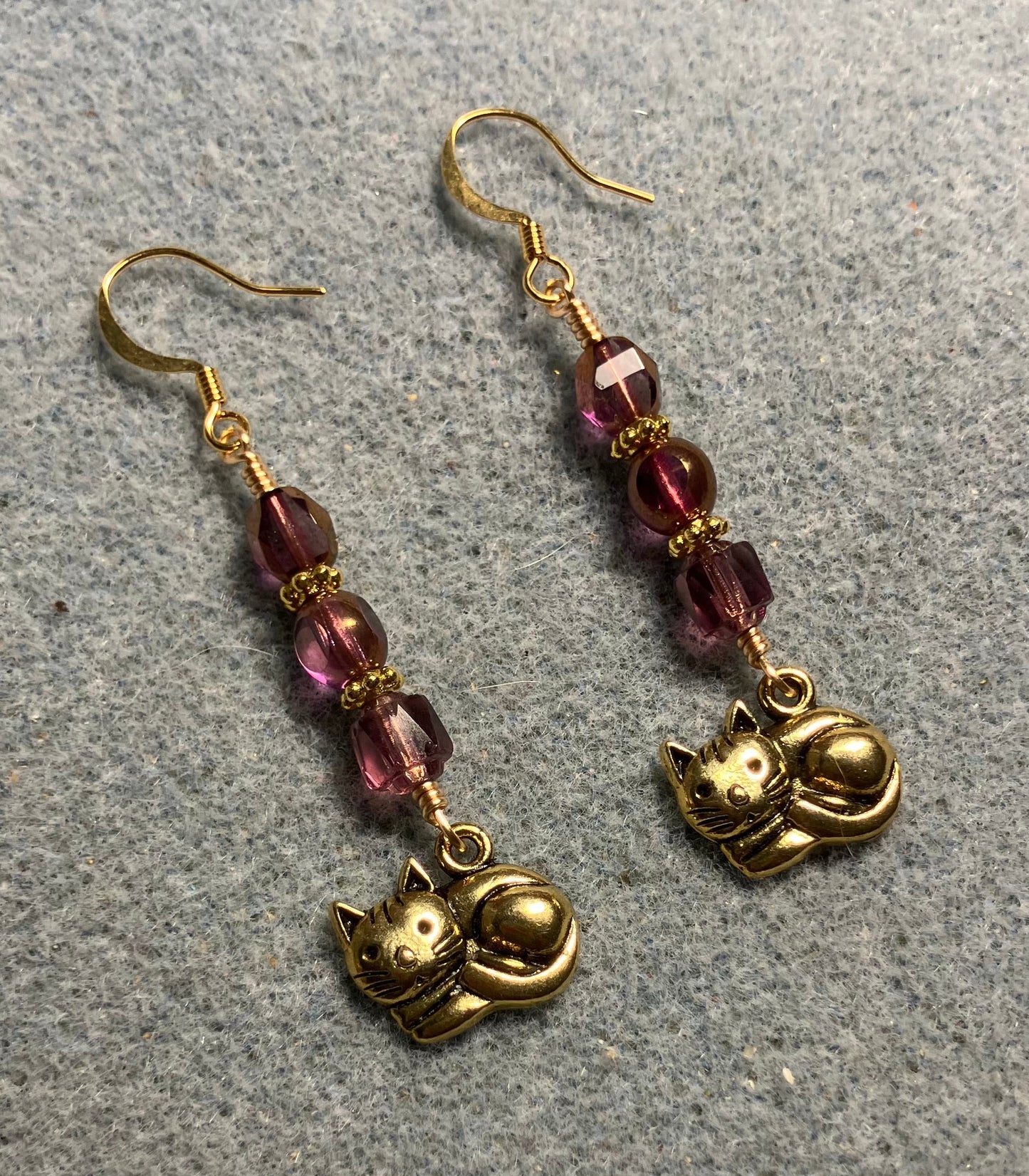Gold sleeping cat charm earrings adorned with violet Czech glass beads