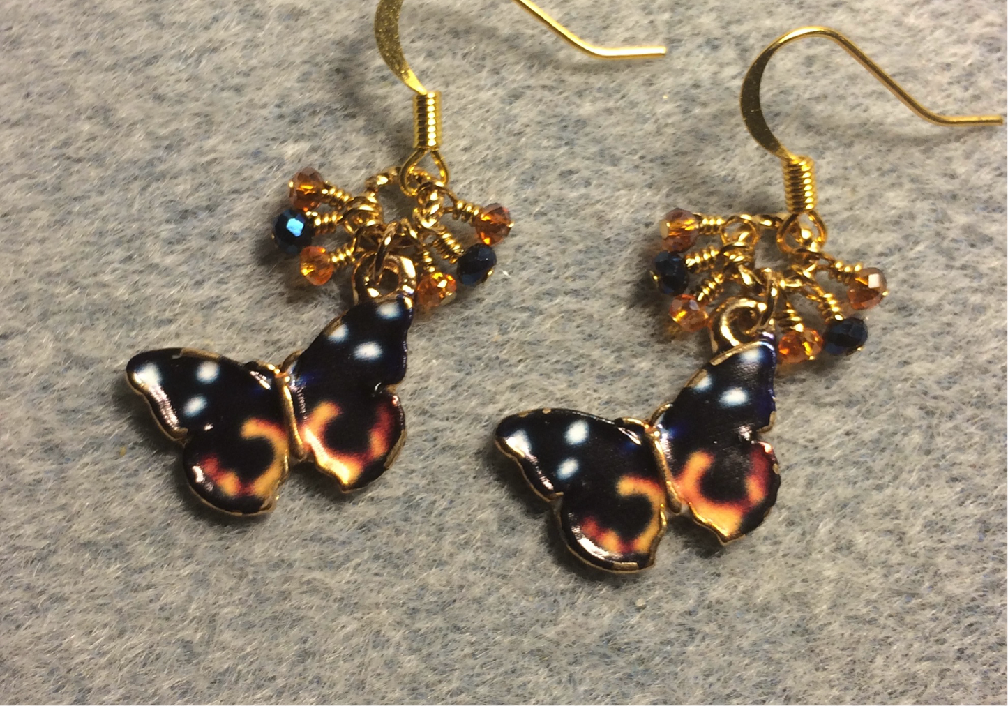 Orange and black enamel butterfly charm earrings adorned with tiny dangling orange and black Chinese crystal beads.