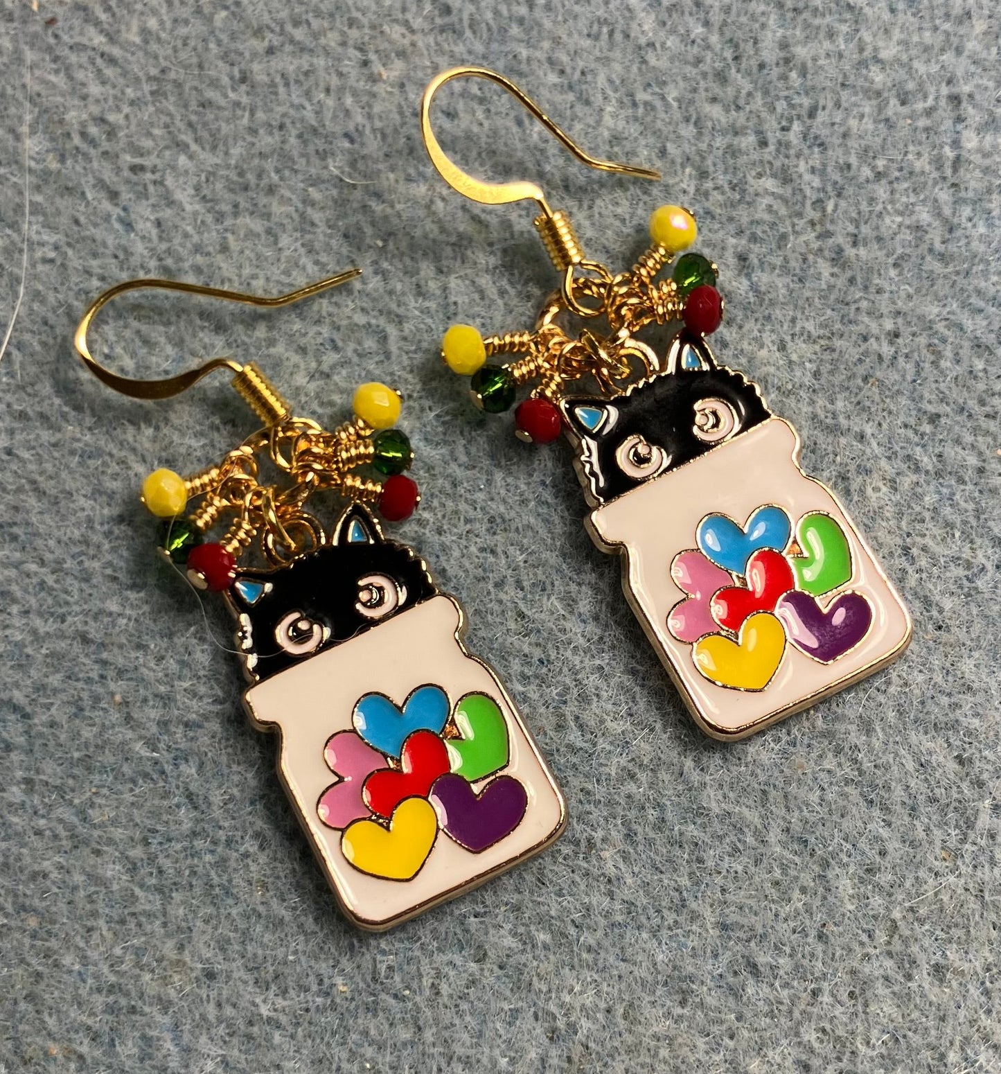 White, black, red, yellow, and green enamel cat charm earrings adorned with tiny dangling red, yellow, and green Chinese crystal beads.