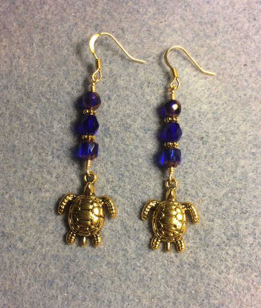 Gold sea turtle charm earrings adorned with dark blue Czech glass beads