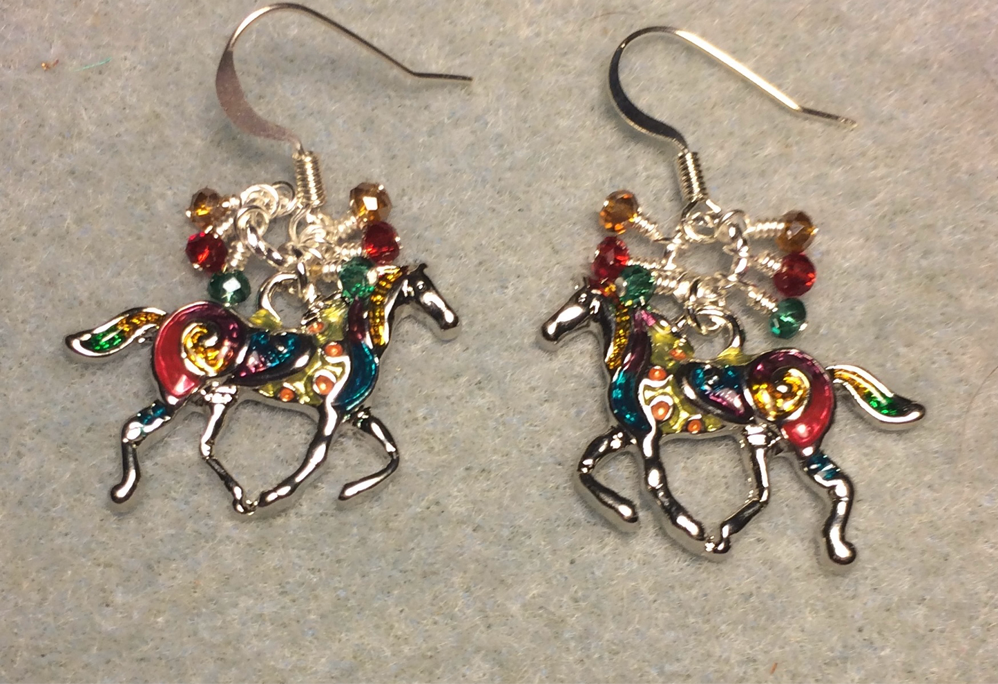Teal, red, and amber enamel horse charm earrings adorned with small dangling teal, red, and amber Czech glass beads.