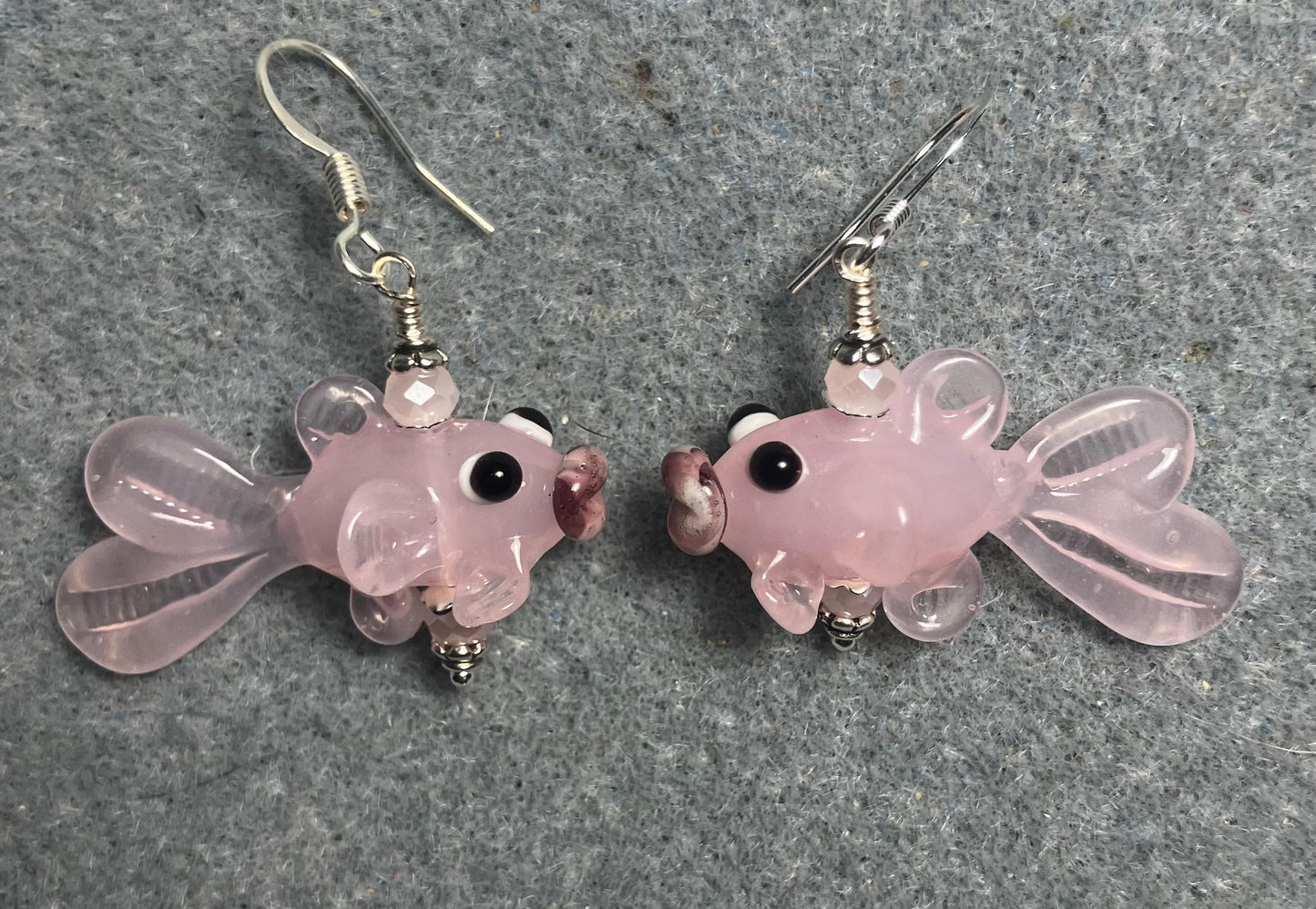 Opaque light pink lamp work fish bead earrings adorned with light pink Chinese crystal beads.