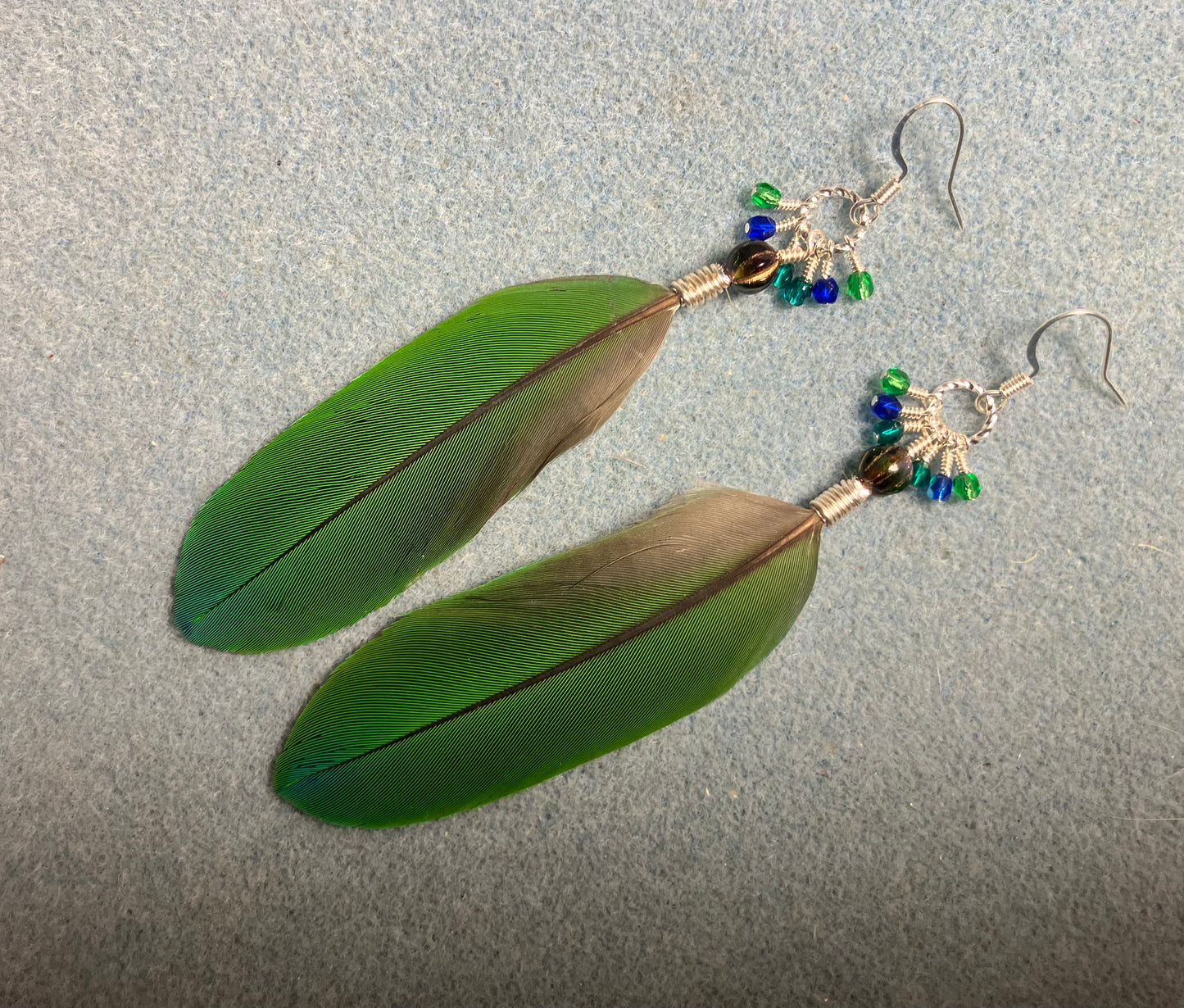 Blue and green blue headed Pionus feather earrings adorned with blue green beads and tiny dangling blue and green Czech glass beads.