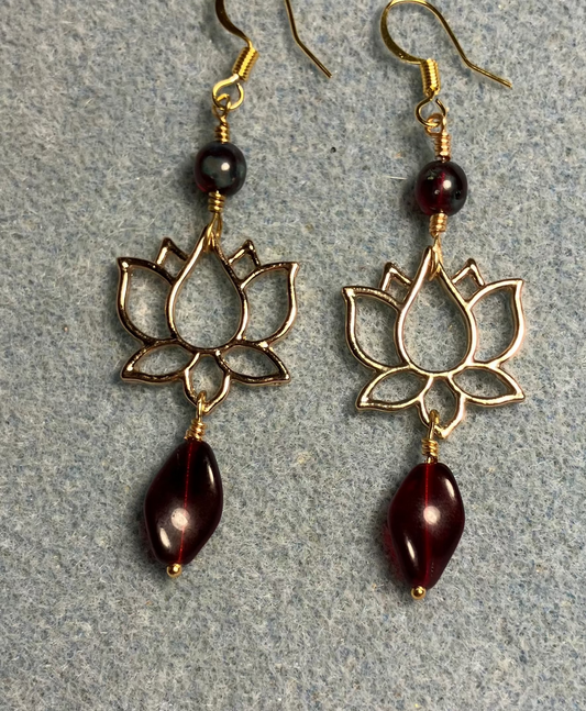 Gold lotus flower connector charm earrings adorned with dark red Czech glass twist beads and dark red Czech glass beads.